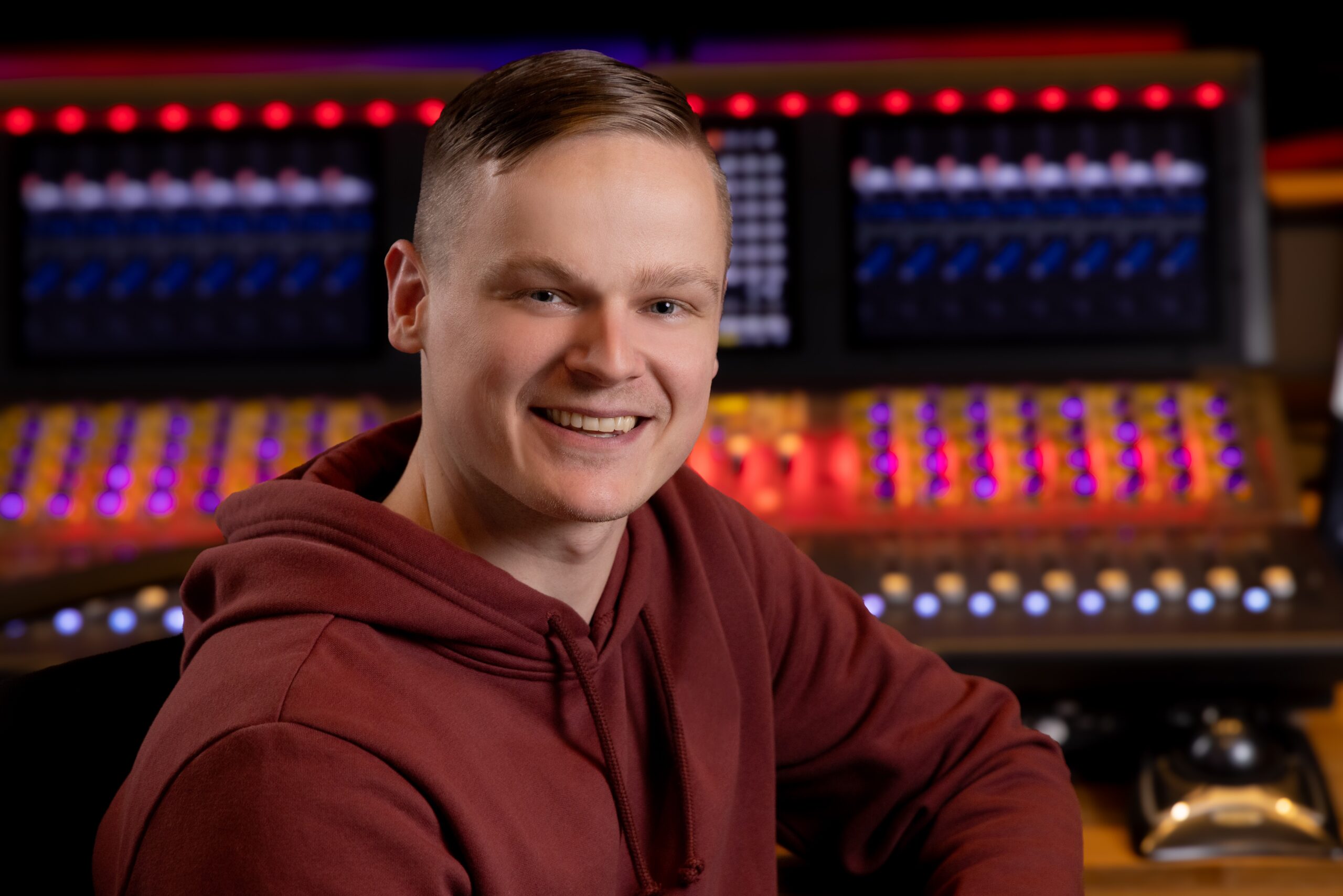 Jonathan Black siting at a mixing booth smiling at the camera