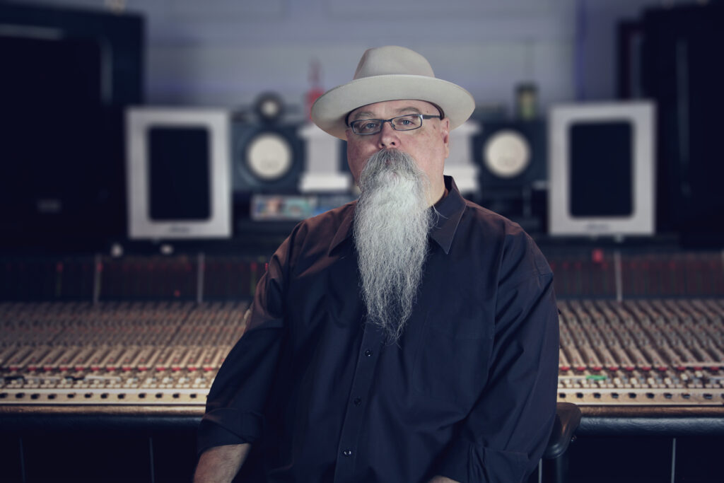 Vance Powel, a white man with a long beard, glasses, and a tan hat, looking at the camera