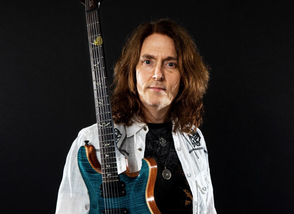 Headshot of Don Carr holding a guitar looking at the camera calmly